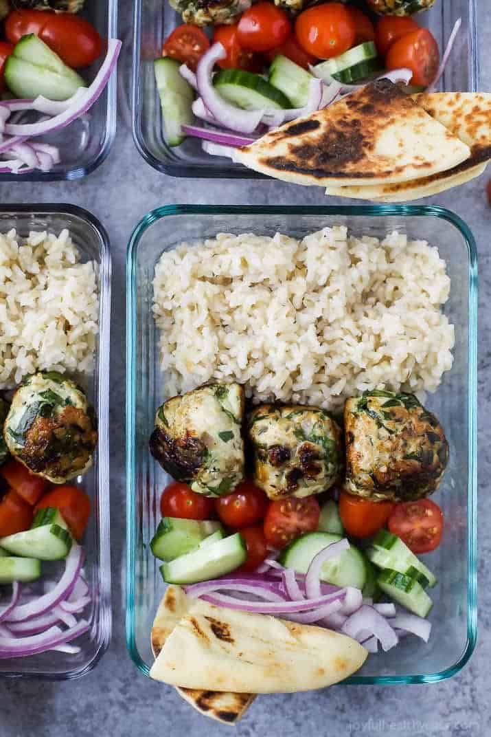 Top view of meal prep containers of Gyro Turkey Meatball Grain Bowls with rice, vegetables and pita bread wedges