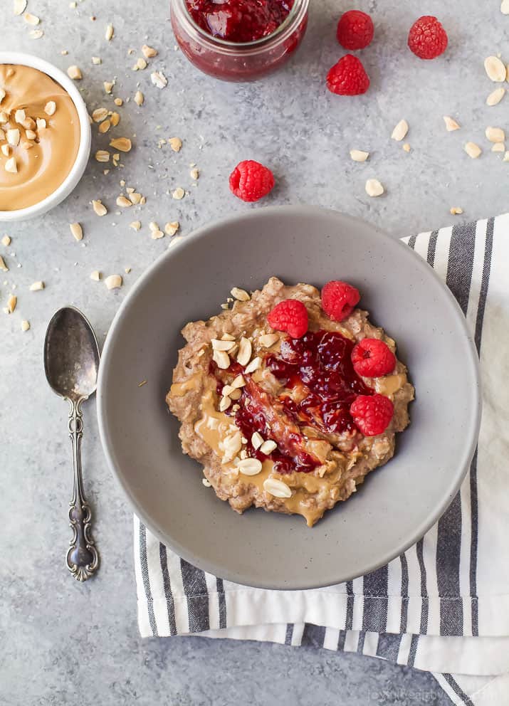 a bowl of oatmeal with raspberry jam and berries on top