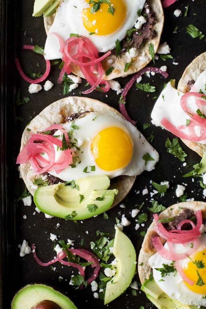 Healthy Huevos Rancheros Breakfast Tostadas topped with creamy avocado and pickled onions. These breakfast tostadas are a delicious breakfast option that are high in protein and fiber with only 292 calories a serving!