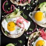 Healthy Huevos Rancheros Breakfast Tostadas topped with creamy avocado and pickled onions. These breakfast tostadas are a delicious breakfast option that are high in protein and fiber with only 292 calories a serving!