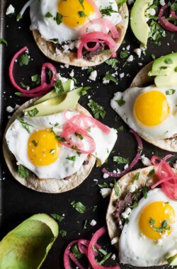 Healthy Huevos Rancheros Breakfast Tostadas topped with creamy avocado and pickled onions. These breakfast tostadas are a delicious breakfast option that are high in protein and fiber with only 292 calories a serving!