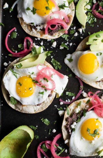 Healthy Huevos Rancheros Breakfast Tostadas topped with creamy avocado and pickled onions. These breakfast tostadas are a delicious breakfast option that are high in protein and fiber with only 292 calories a serving!