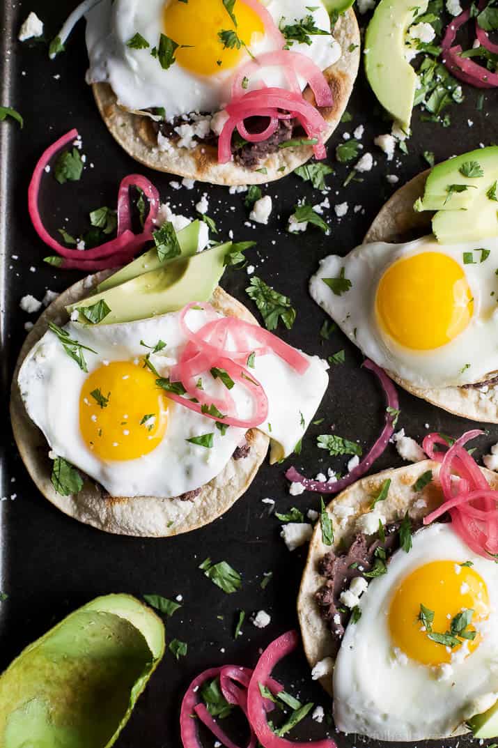 Healthy Huevos Rancheros Breakfast Tostadas topped with creamy avocado and pickled onions. These breakfast tostadas are a delicious breakfast option that are high in protein and fiber with only 292 calories a serving!