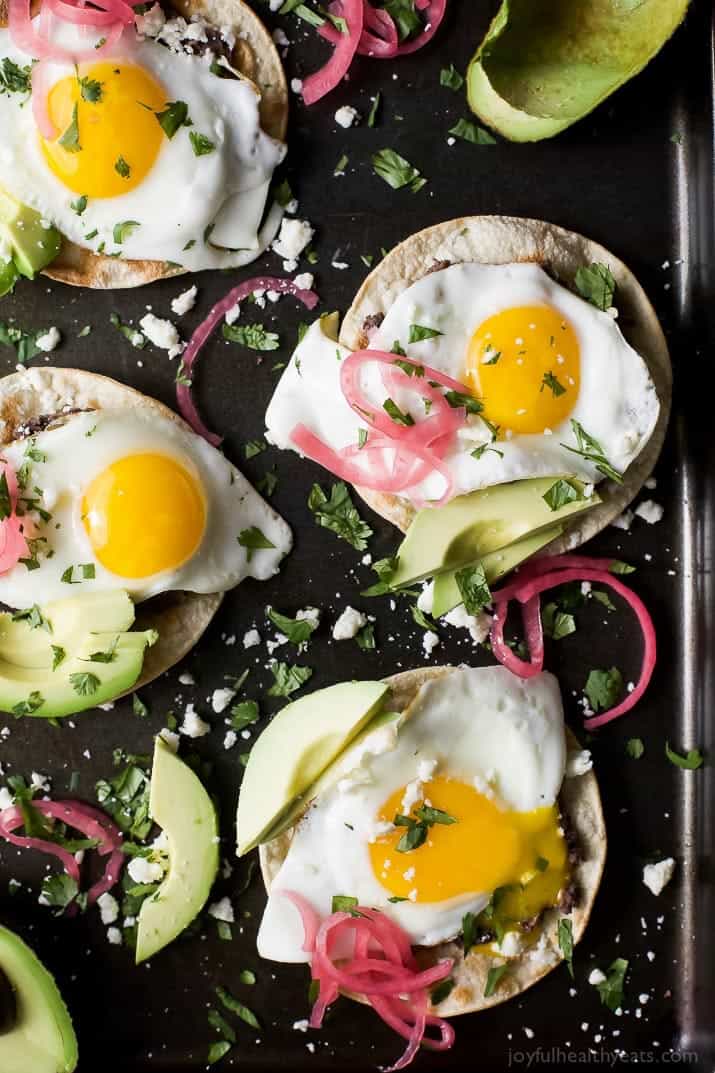 Healthy Huevos Rancheros Breakfast Tostadas topped with creamy avocado and pickled onions. These breakfast tostadas are a delicious breakfast option that are high in protein and fiber with only 292 calories a serving!