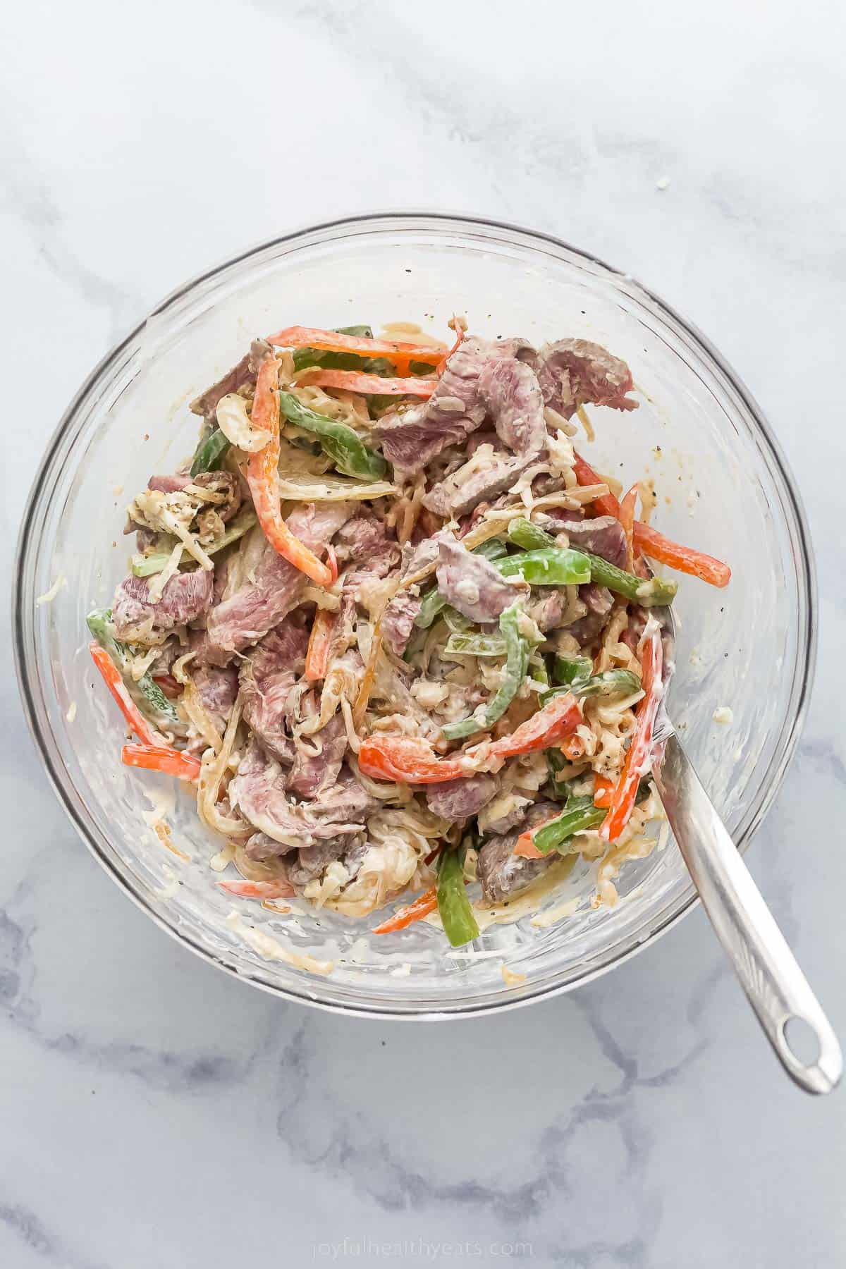 sliced steak and vegetables tossed in a cream sauce in a bowl