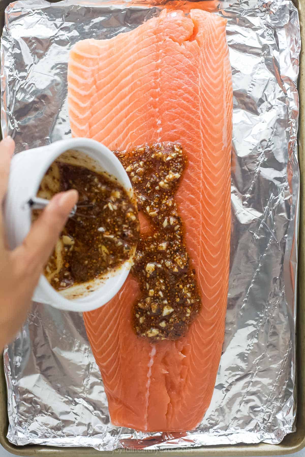 Pouring the sauce over the salmon.