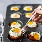 prosciutto baked eggs cups in a muffin tin after coming out of the oven