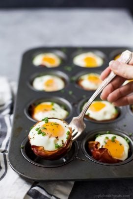 prosciutto baked eggs cups in a muffin tin after coming out of the oven