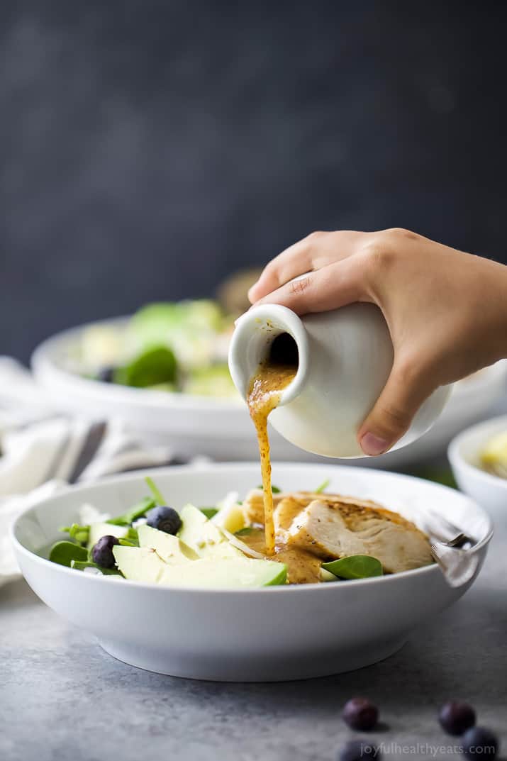 Dressing being poured over a bowl of Grilled Avocado Mango Chicken Salad