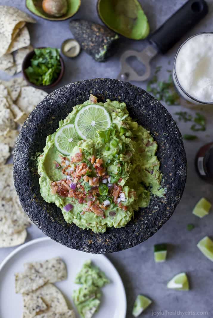 a stone bowl with guacamole and bacon garnish