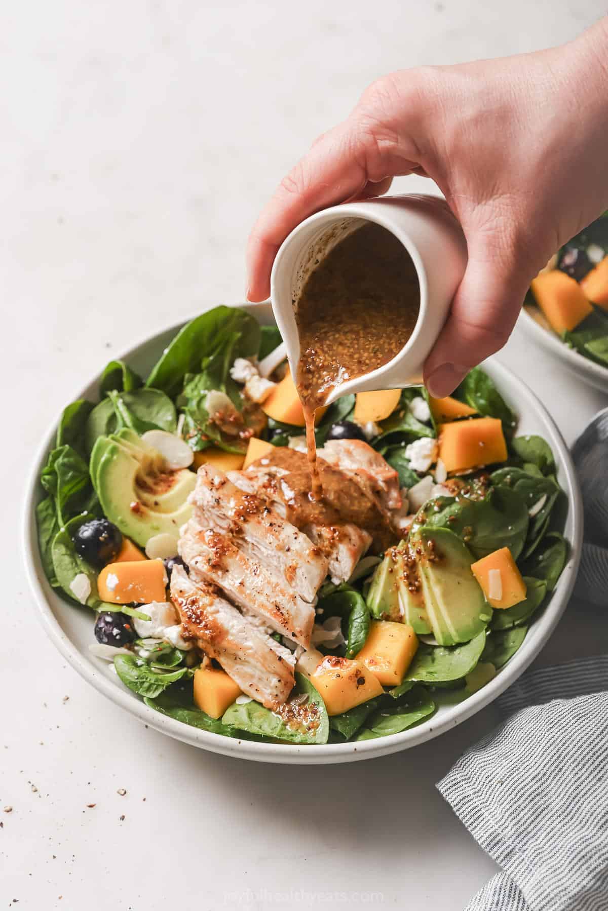 Pouring dressing over the avocado salad.