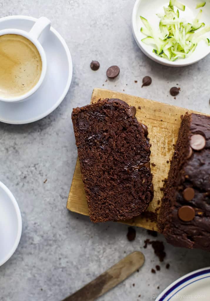 Top view of a slice of Double Chocolate Zucchini Bread on a wooden board next to a cup of espresso