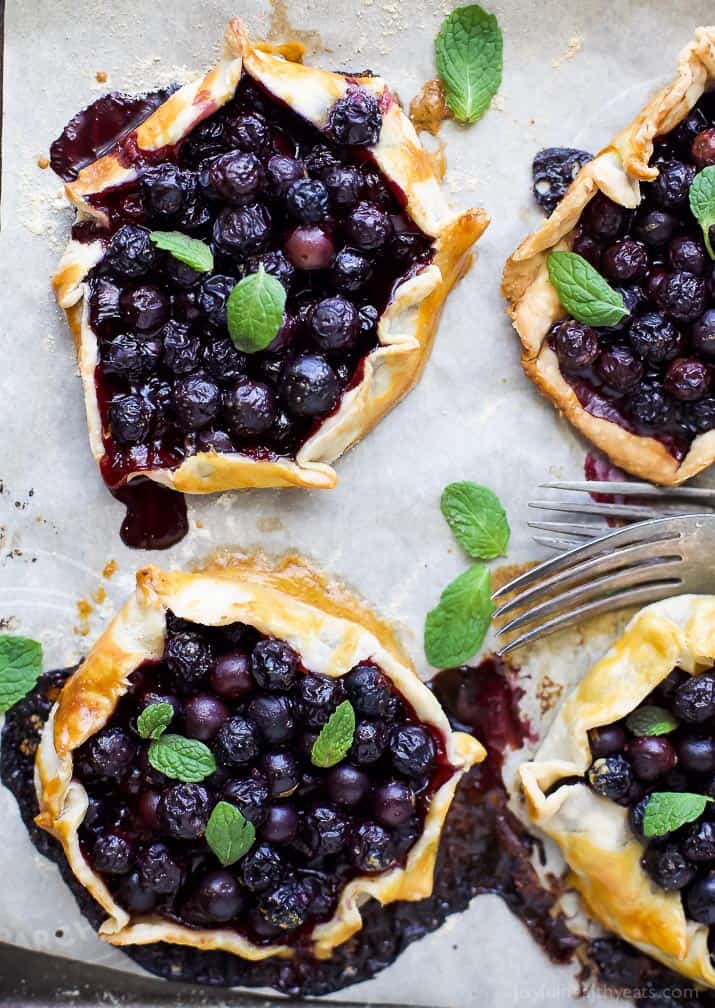 Top view of four Fresh Mini Blueberry Galettes on parchment paper