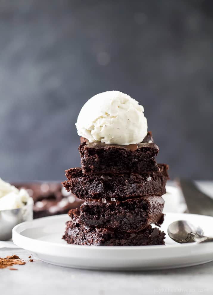 A stack of fudgy almond butter brownies with a scoop of vanilla ice cream on top