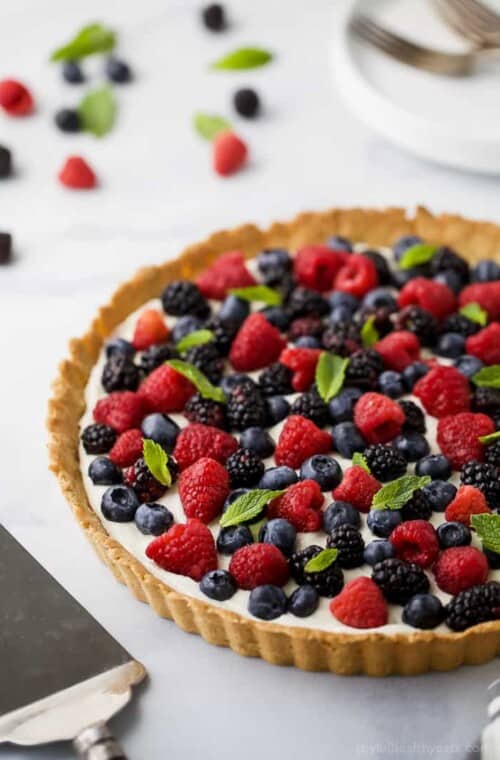 Gluten Free Berry Tart filled with a creamy greek yogurt cheesecake filling and an Almond Crust. This beautiful Berry Tart is a light dessert that's perfect for the summer!