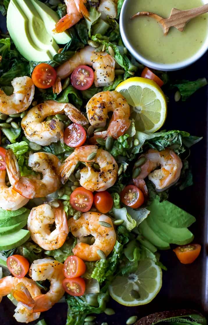 Top view of Grilled Shrimp Caesar Salad with a bowl of homemade Caesar dressing