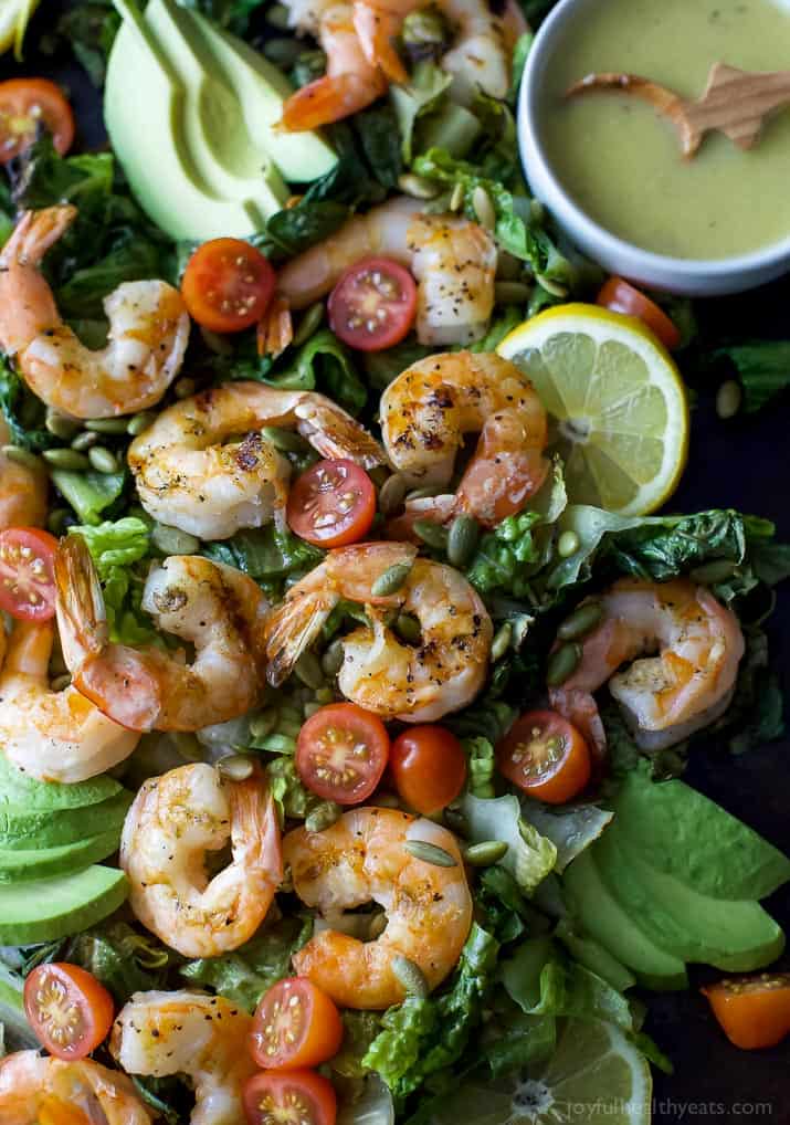 Top view of Grilled Shrimp Caesar Salad with a bowl of homemade Caesar dressing