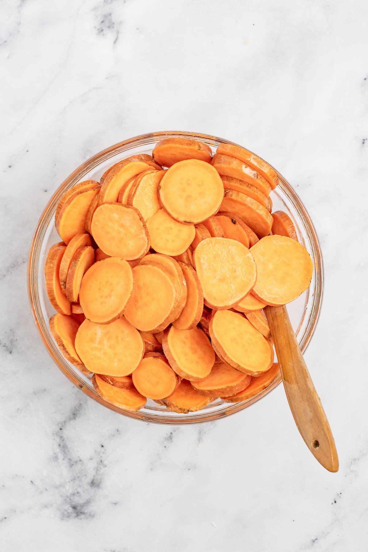 Mixing the sweet potato slices with oil. 