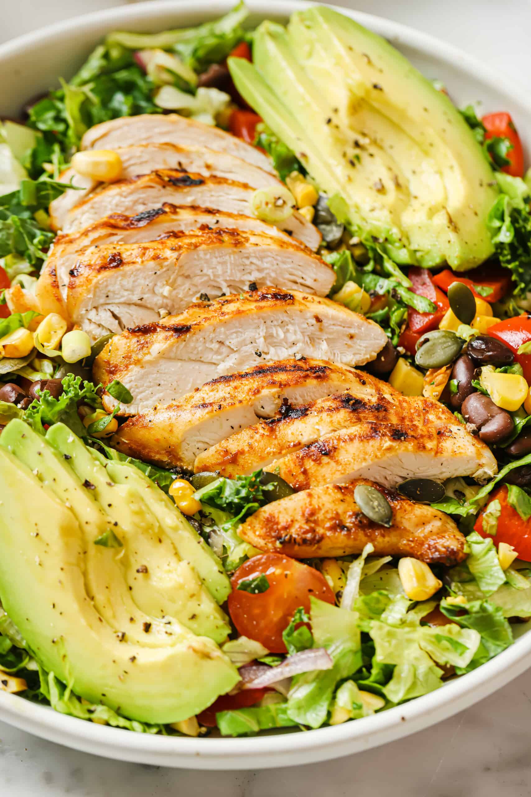 Chicken chopped salad in a bowl with sliced avocado and poblano dressing. 