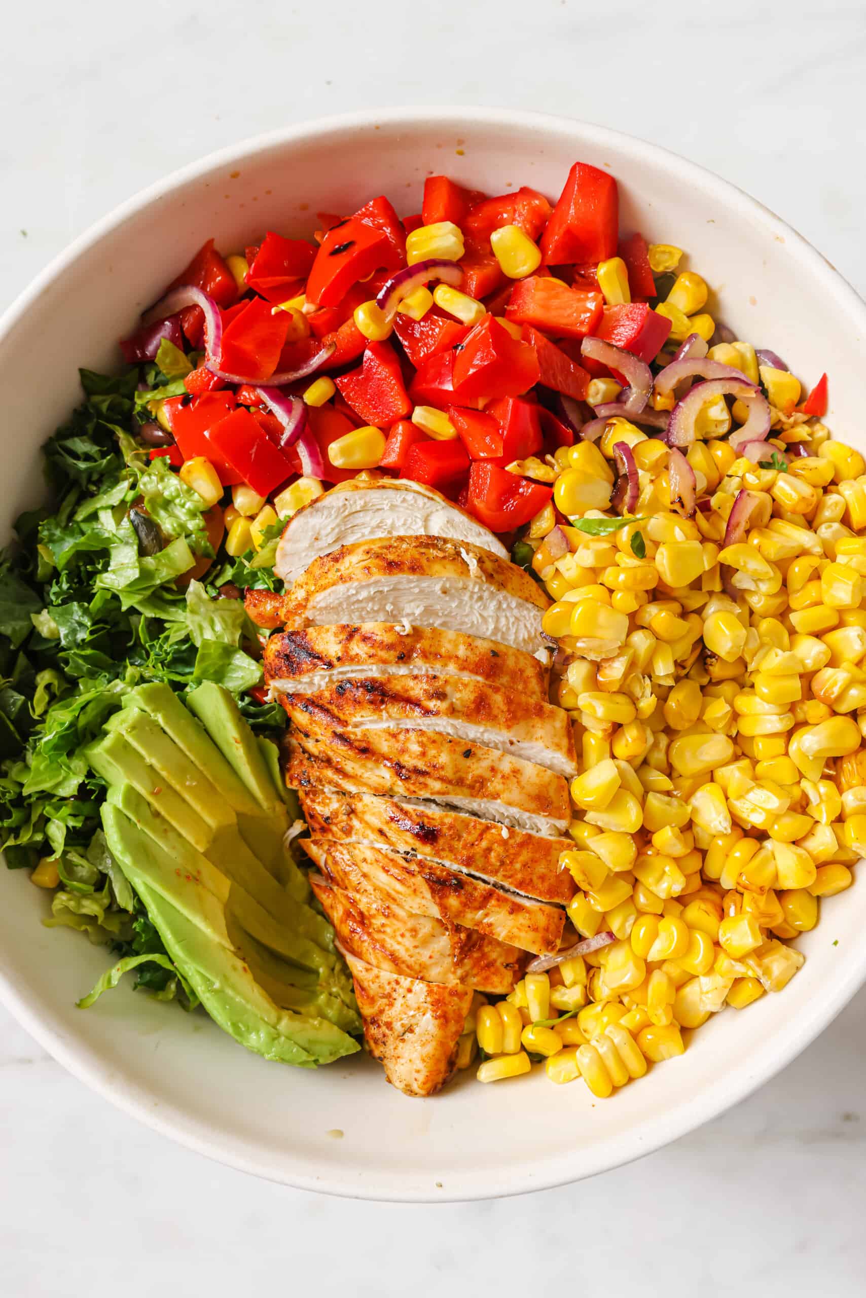 Adding all of the salad ingredients to a large bowl.