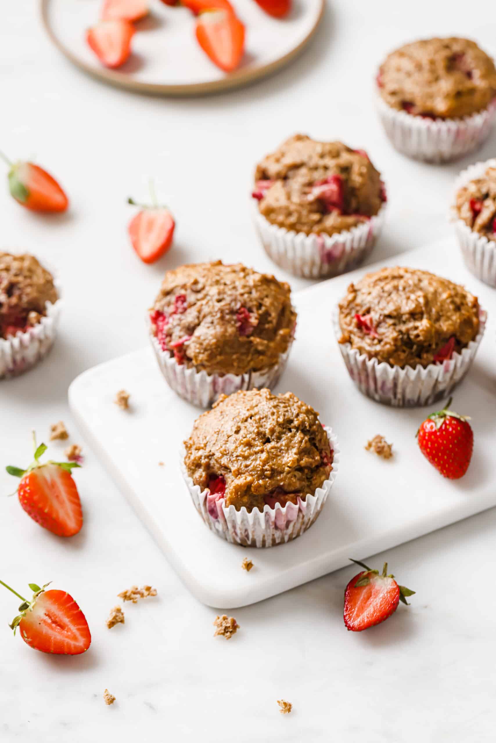 Three homemade strawberry muffins on a white marble slab. 