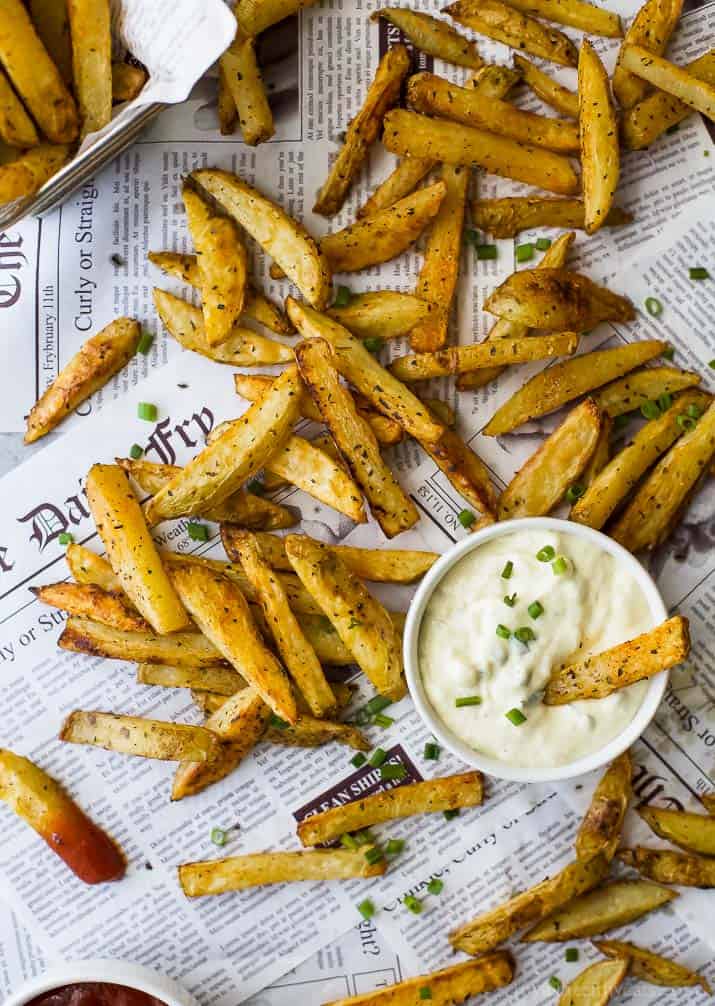 Crispy Oven Baked Fries on newspaper with a cup of Roasted Garlic Aioli
