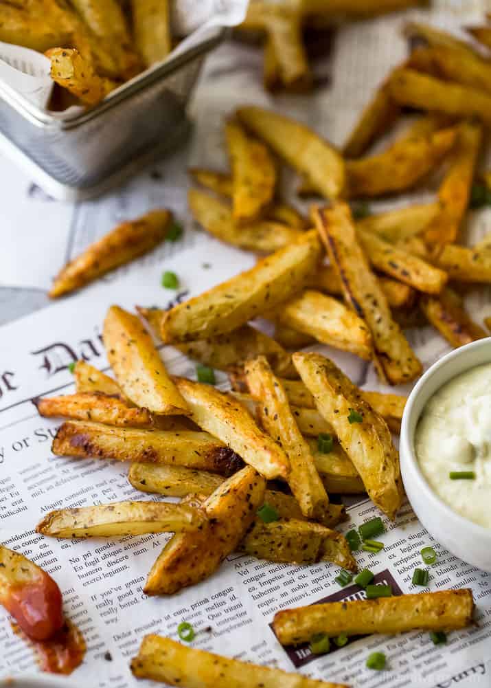 Crispy Oven Baked Fries on newspaper with a cup of Roasted Garlic Aioli