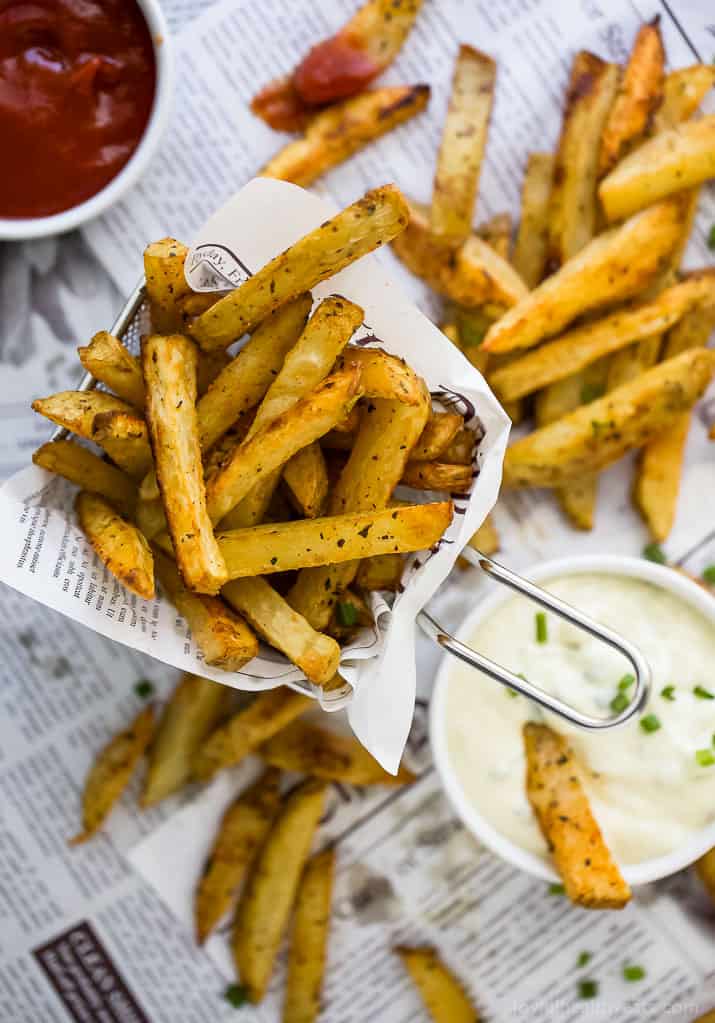 A paper-lined basket of Crispy Oven Baked Fries with a cup of Garlic Aioli