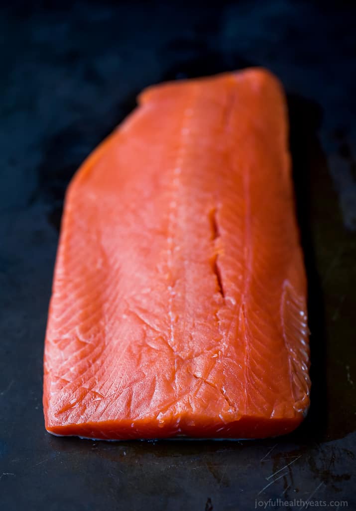 A raw one-pound fish fillet sitting on a black surface.