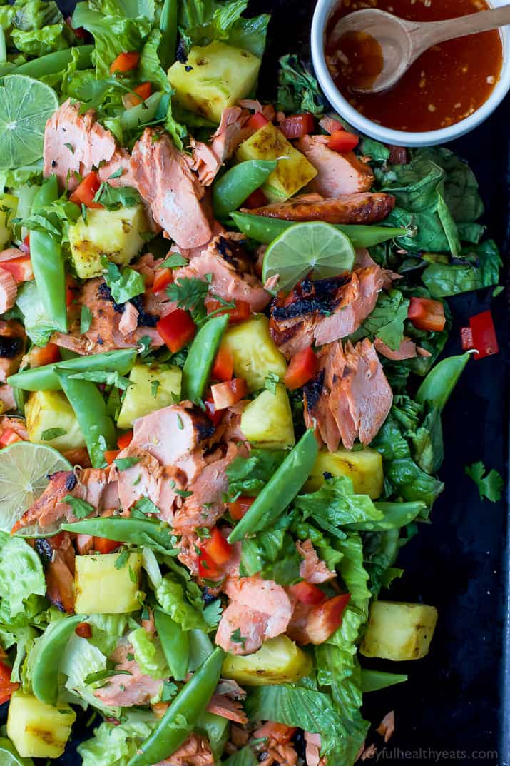 A platter full of salmon salad with some honey sriracha sauce in a small bowl on the side