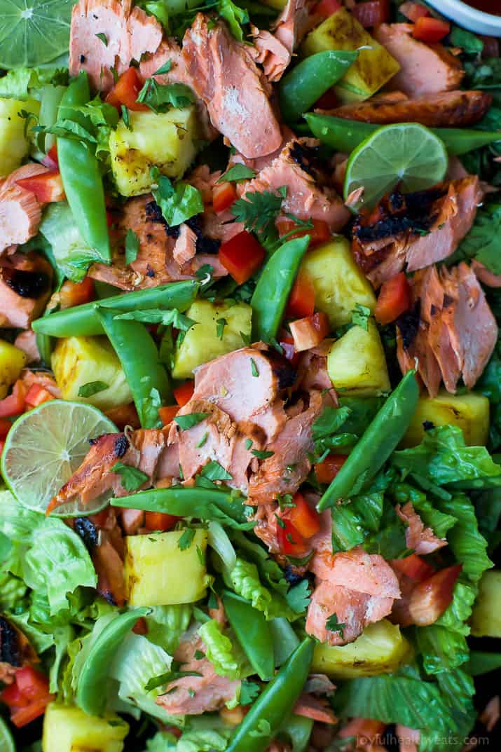A close-up shot of a homemade salmon salad with snap peas, grilled pineapple and romaine lettuce.