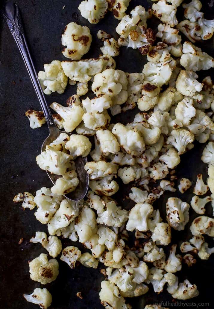 Roasted Cauliflower Salad tossed with a Curry Yogurt Sauce, dry cranberries and pepitas! This healthy salad is easy to make and loaded with flavor! It's the perfect side dish to bring to your next party - definitely a conversation starter.