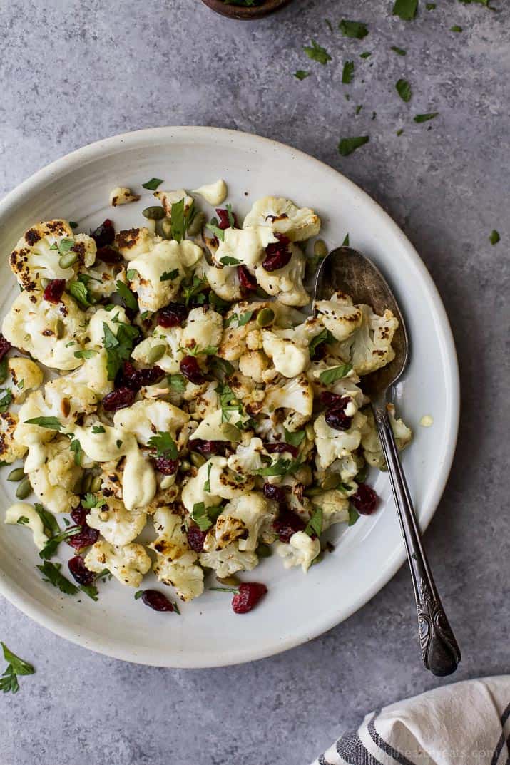 Roasted Cauliflower Salad tossed with a Curry Yogurt Sauce, dry cranberries and pepitas! This healthy salad is easy to make and loaded with flavor! It's the perfect side dish to bring to your next party - definitely a conversation starter.