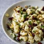 Roasted Cauliflower Salad tossed with a Curry Yogurt Sauce, dry cranberries and pepitas! This healthy salad is easy to make and loaded with flavor! It's the perfect side dish to bring to your next party - definitely a conversation starter.