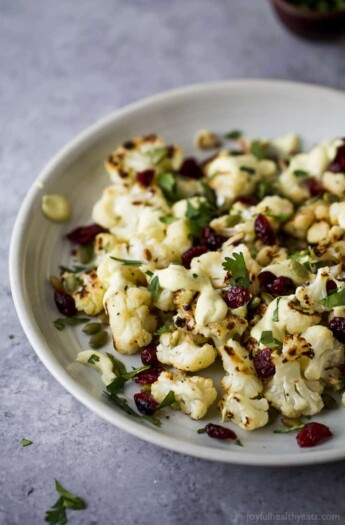 Roasted Cauliflower Salad tossed with a Curry Yogurt Sauce, dry cranberries and pepitas! This healthy salad is easy to make and loaded with flavor! It's the perfect side dish to bring to your next party - definitely a conversation starter.