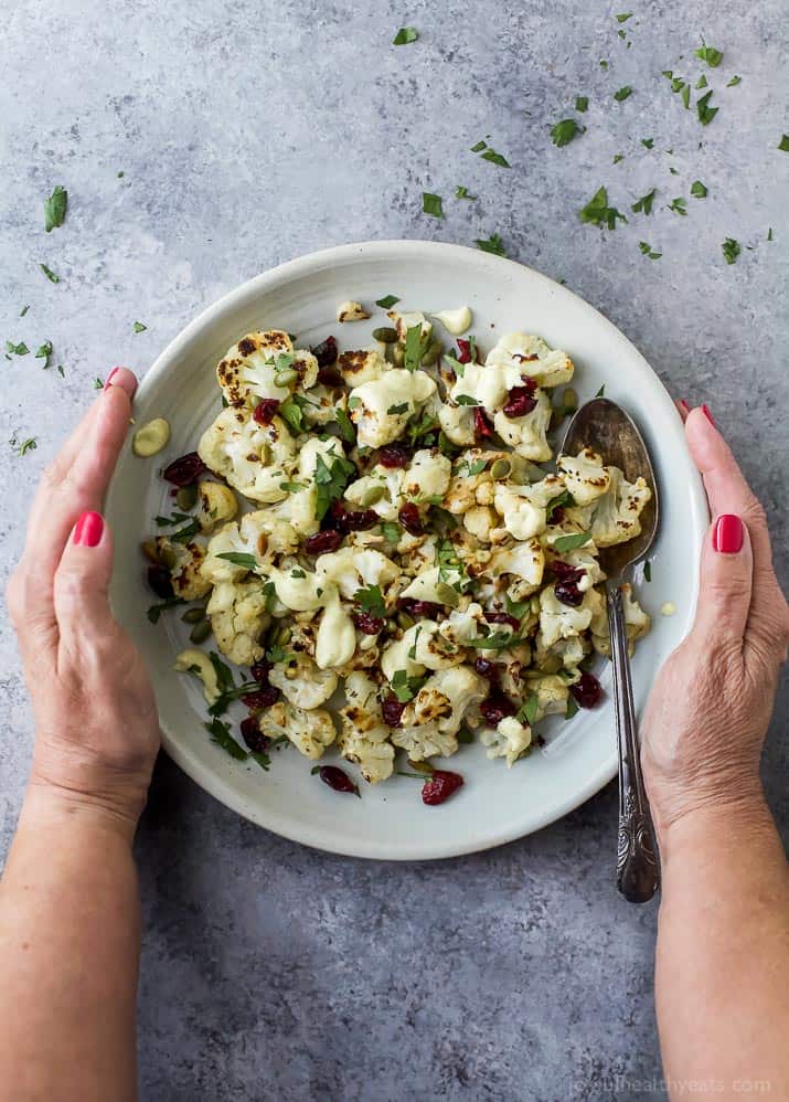 Roasted Cauliflower Salad tossed with a Curry Yogurt Sauce, dry cranberries and pepitas! This healthy salad is easy to make and loaded with flavor! It's the perfect side dish to bring to your next party - definitely a conversation starter.