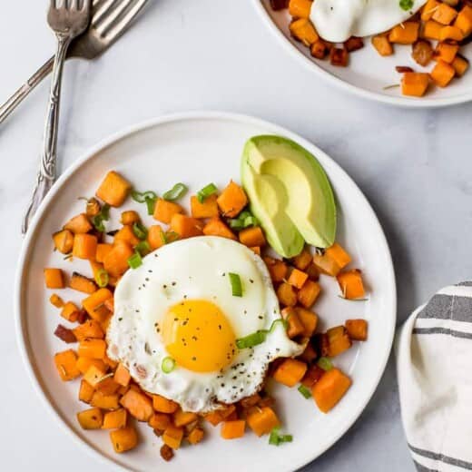 paleo sweet potato hash & eggs on a plate with an avocado