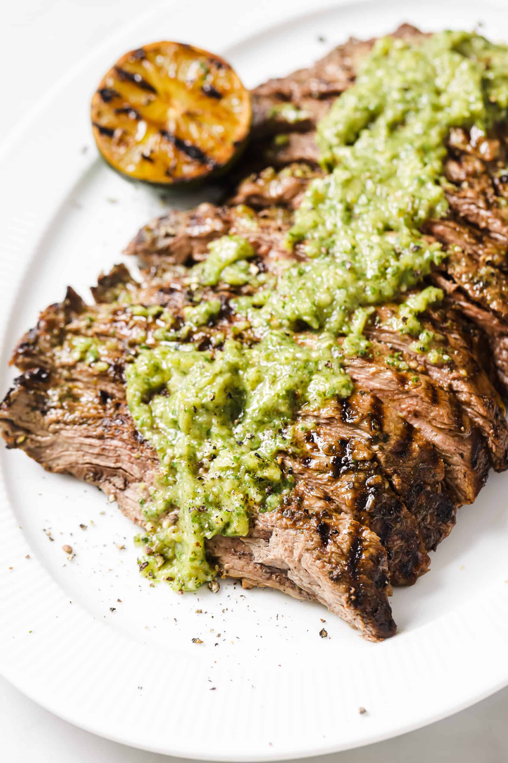 Close-up of grilled steak with salsa verde. 
