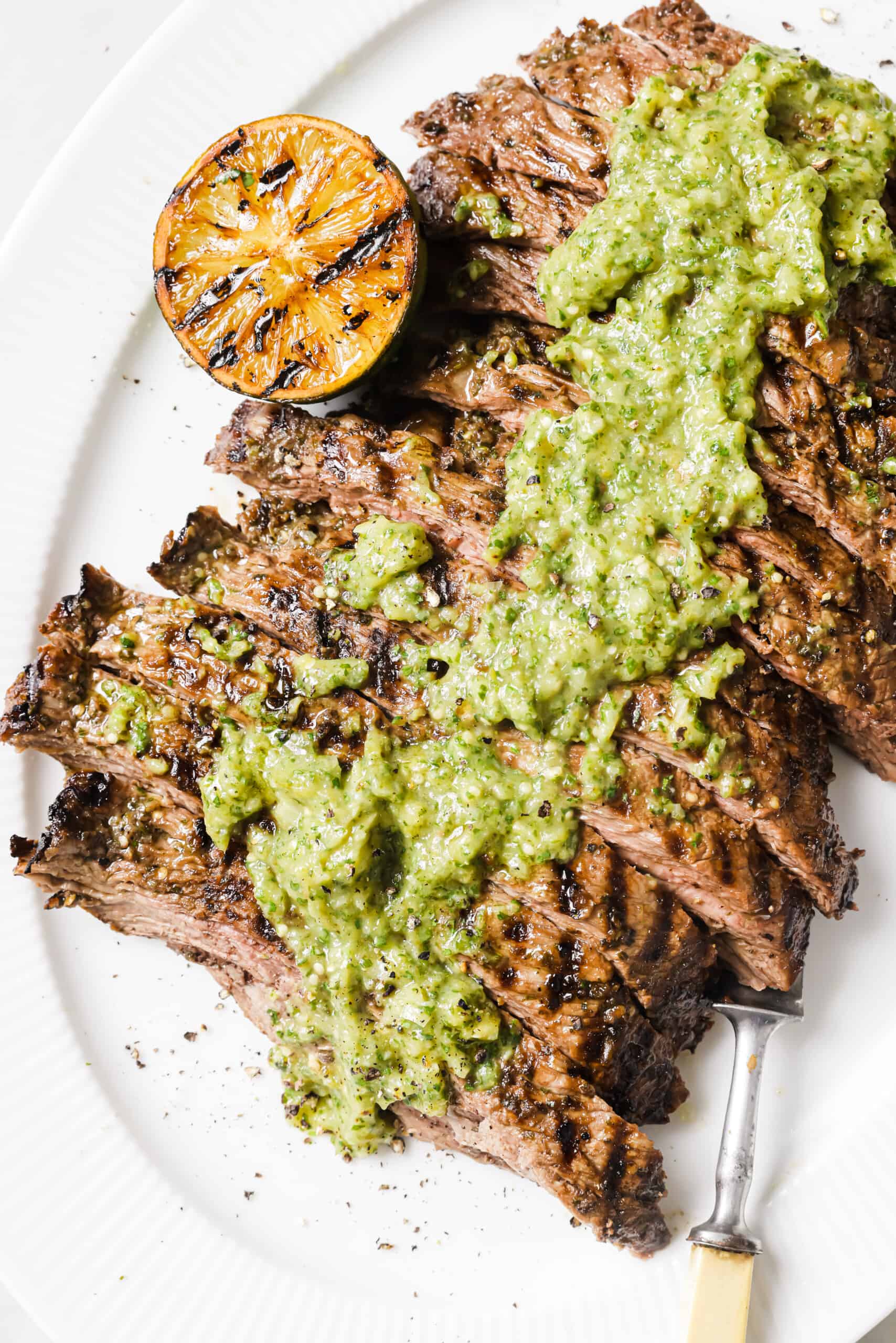 This easy carne asada recipe with salsa verde will be your new favorite Mexican dinner. Easy to make and super juicy, it's the perfect dish! Sliced grilled steak with sauce on top.