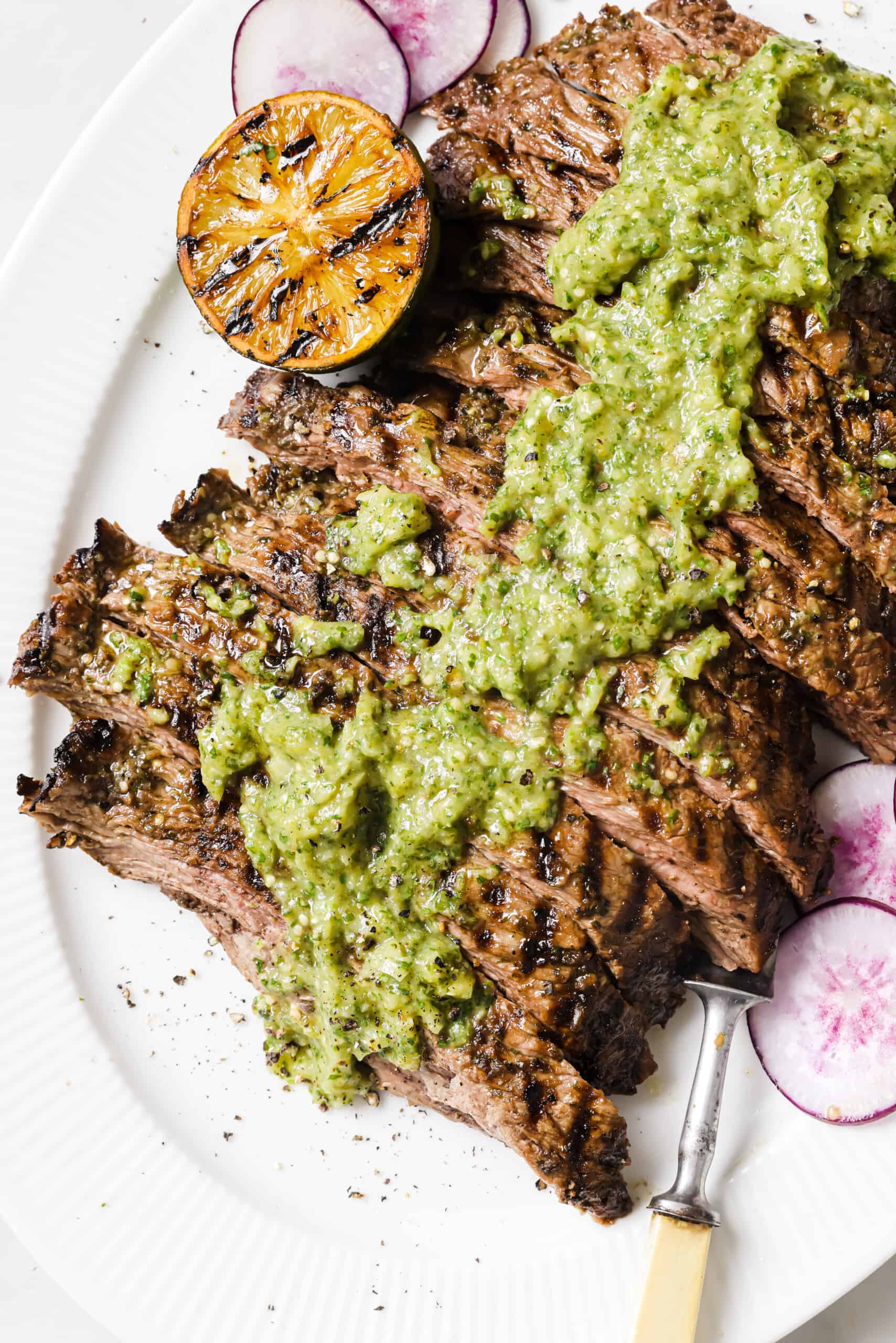 This easy carne asada recipe with salsa verde will be your new favorite Mexican dinner. Easy to make and super juicy, it's the perfect dish! Sliced carne asada recipe with salsa on top.