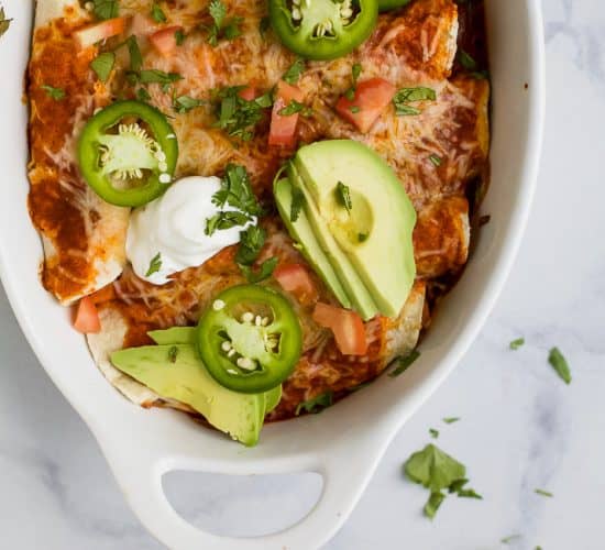 Gluten Free Sweet Potato Black Bean Enchiladas covered in a smoky red chili sauce and gooey cheese. Simple ingredients and lots of flavor make these black bean enchiladas a must try dinner recipe!