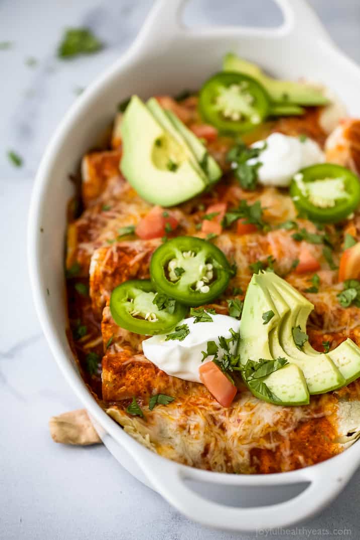 Sweet potato black bean enchiladas with jalapeños, sour cream, and diced avocado on top.