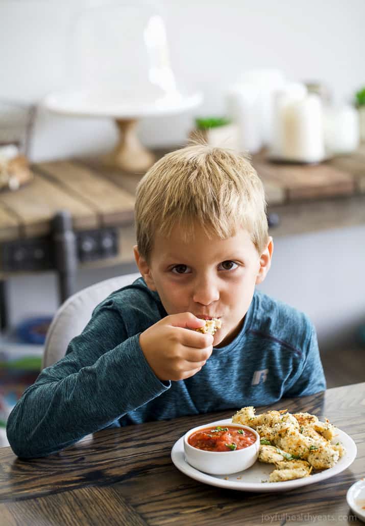 A little boy eating Baked Chicken Parmesan Bites with marinara sauce