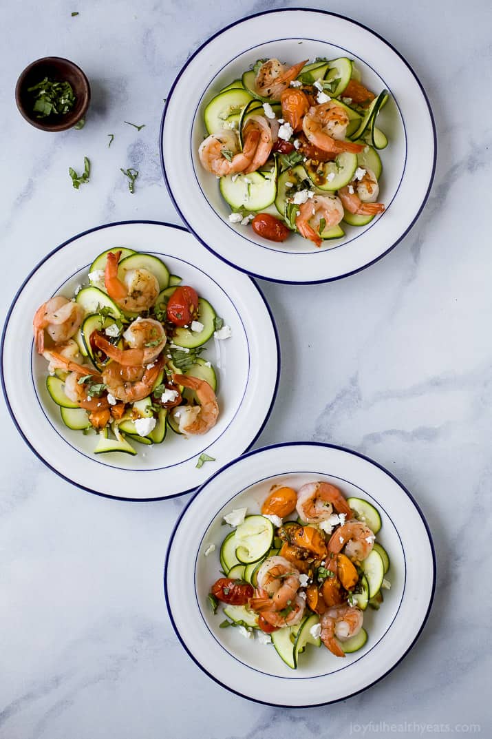Top view of three bowls of Zucchini Pasta topped with shrimp, grape tomatoes and goat cheese