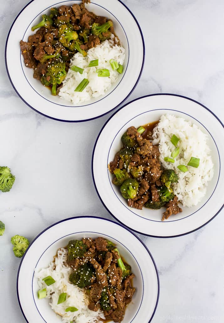 Top view of three bowls of Mongolian Beef and broccoli with white rice