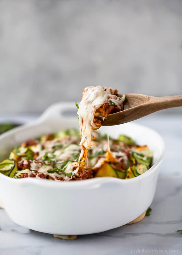 This saucy zucchini roll up recipe with ground beef, tomato sauce, and creamy ricotta is a pasta-free, Italian-inspired dinner. Catch a melted zucchini roll with a wooden spoon.