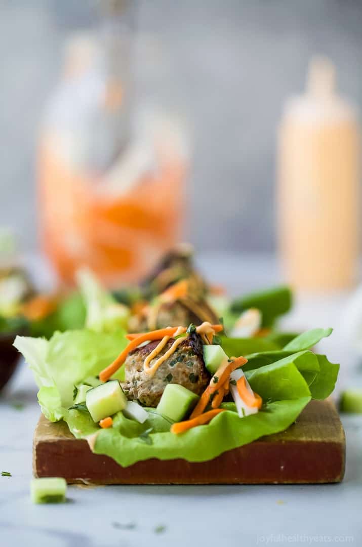 Close-up view of a Banh Mi Lettuce Wrap on a wooden board with turkey meatballs served on a lettuce wrap with pickled vegetables and sriracha mayo