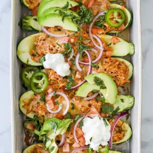 Easy Chicken Enchilada Zucchini Boats with red chili sauce and melted cheese.  A 30 minute meal that's gluten free, low carb, high protein and perfect for a weeknight dinner.