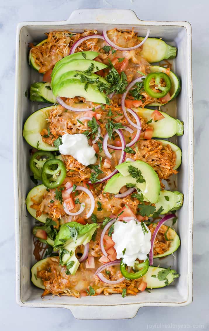 Top view of a pan of Chicken Enchilada Zucchini Boats with red chili sauce and melted cheese