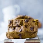 A stack of three slices of chocolate chip pumpkin bread on a piece of parchment paper